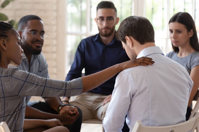 A group of professionals engaged in conversation with one person touching another's shoulder