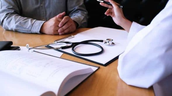 A doctor having a conversation with a patient, stethoscope placed on the table