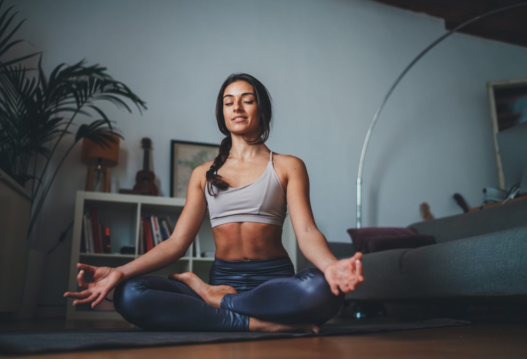 A woman peacefully meditates in a yoga pose, finding serenity and balance within herself