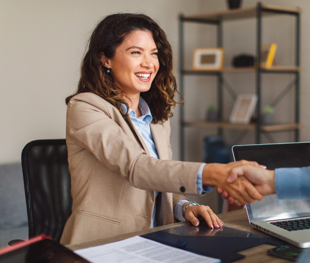 A woman and a man shaking hands at a desk