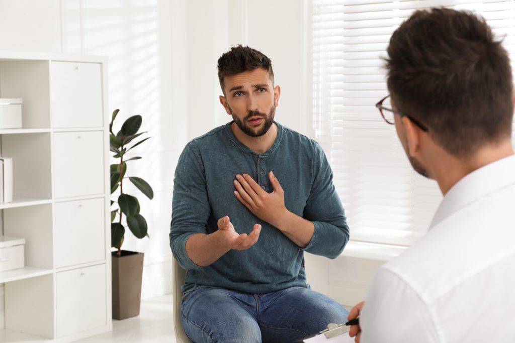 Two men discussing chest pain with a doctor, using hand gestures