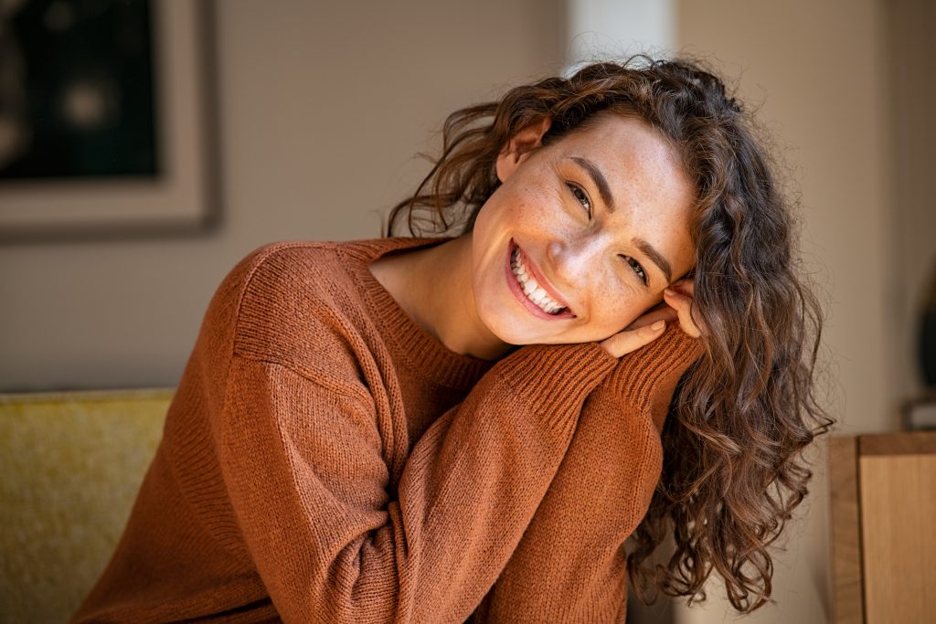 A happy woman sitting on a couch, smiling warmly