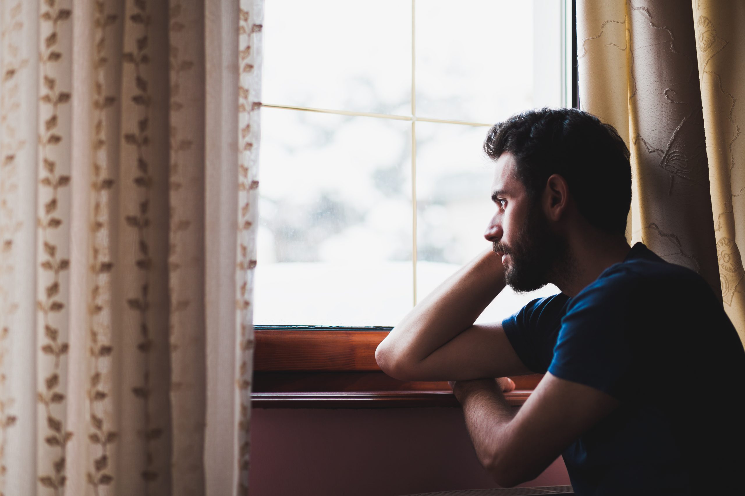 A man gazes out of a window, lost in thought