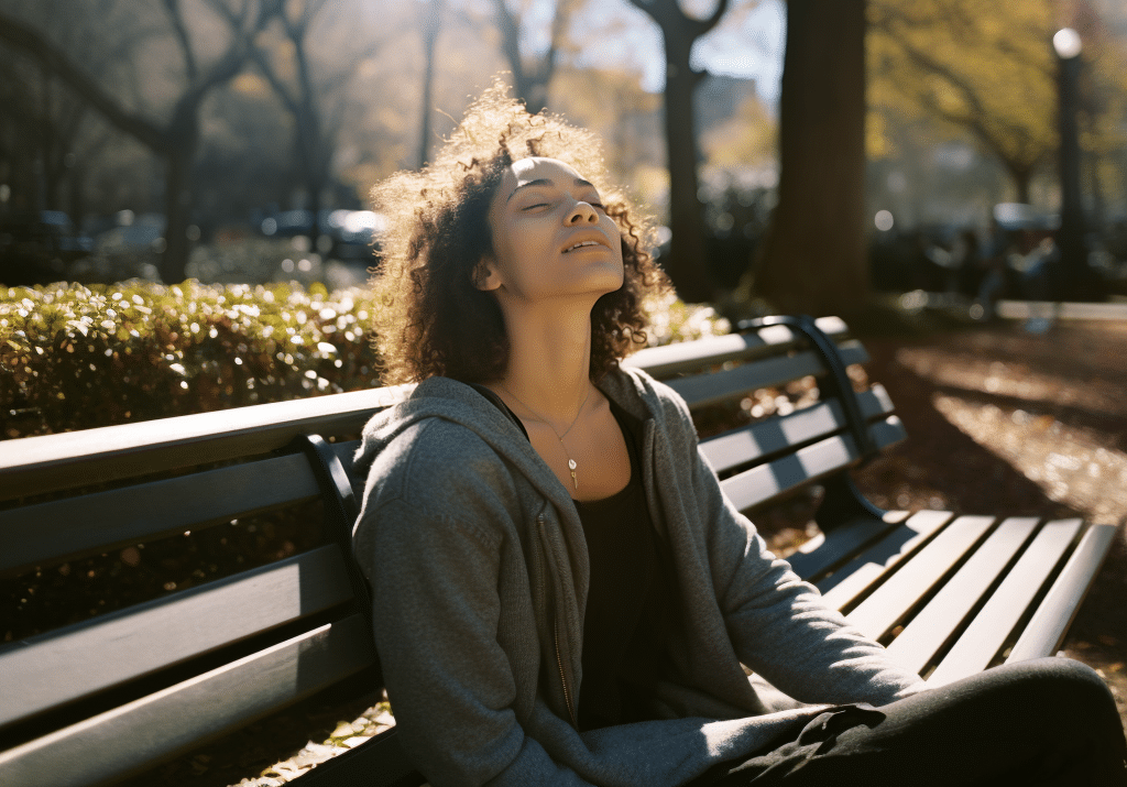 A woman peacefully sits on a bench, closing her eyes in relaxation